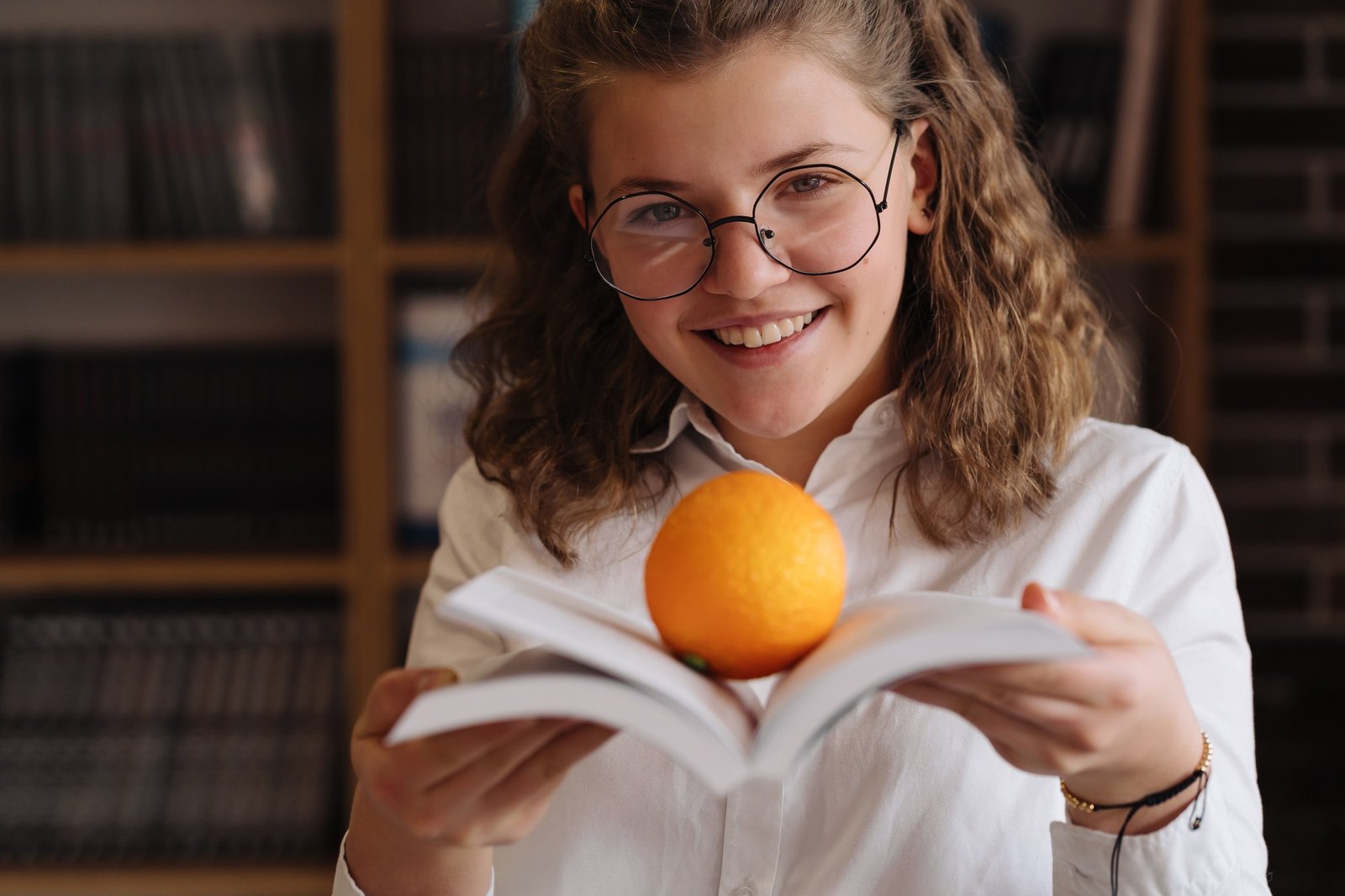 Fresh ideas. Woman holding an opened book with an orange on it