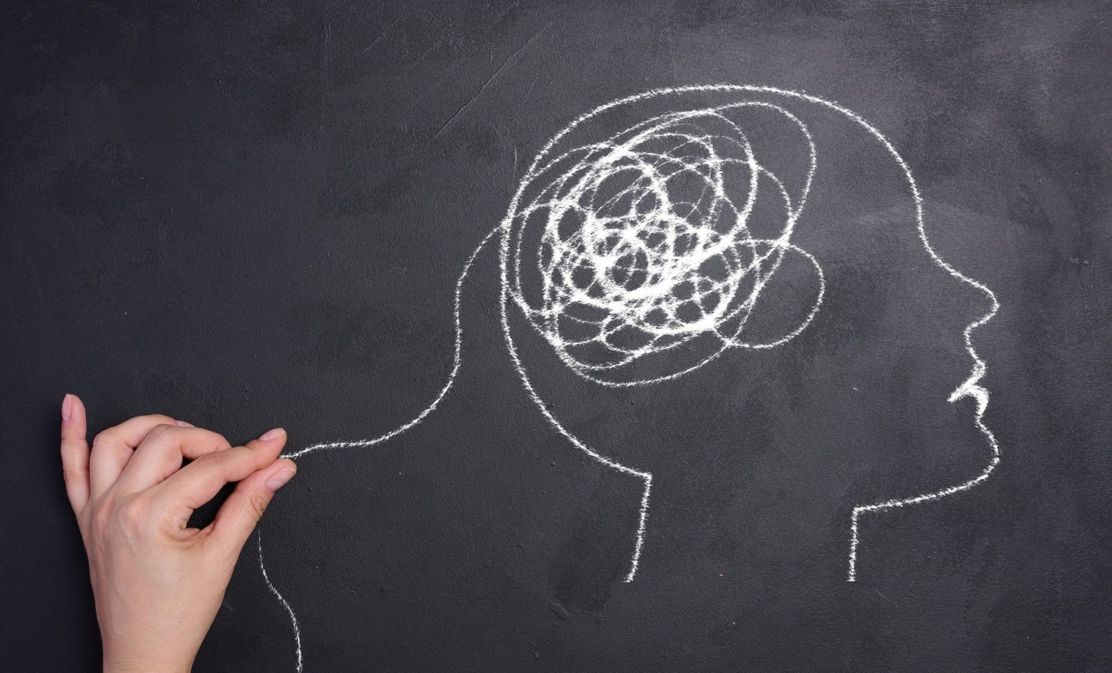 Profile of a human head with a tangled spiral in the brain area. The head is drawn in white chalk.
